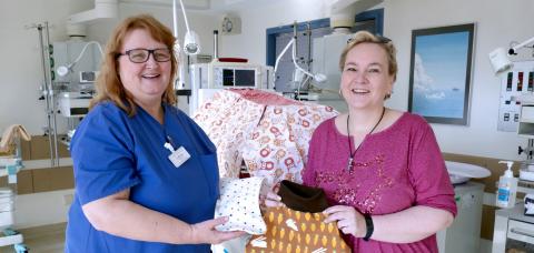 Kinderkrankenpflegerin Eva Beining und Michaela Bruns zeigen die liebevoll genähten Kleidungsstücke und Decken.